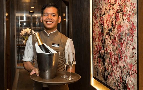 A butler holding a bottle of Champagne on board the Scenic Spirit ship.