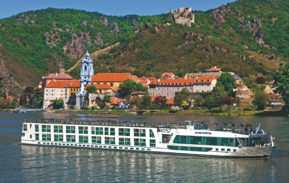 A river ship cruising down a river. A castle can be seen in the background