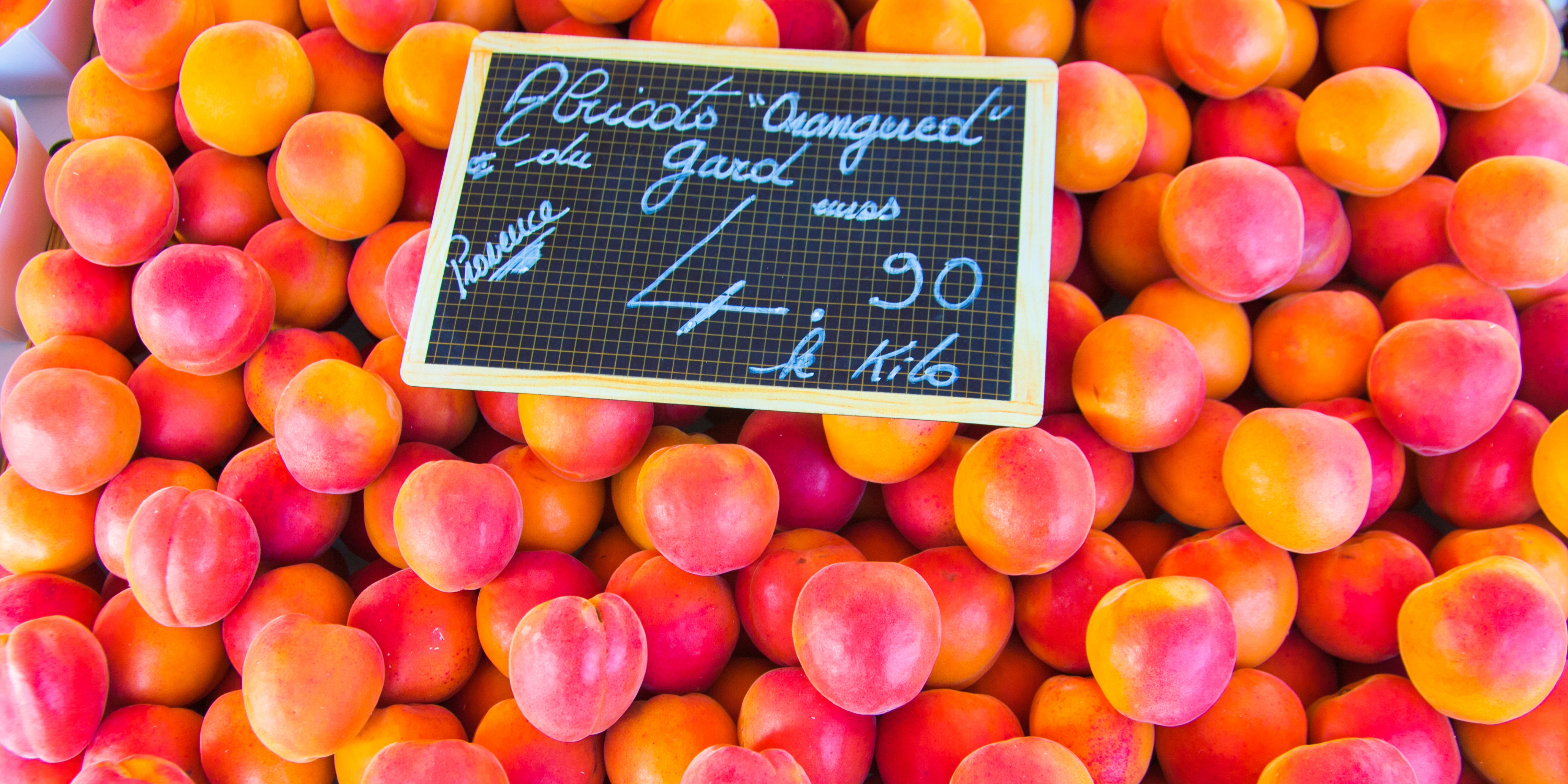 An exquisite collection of plums, glistening under the sun, beautifully showcased at a charming market setting.