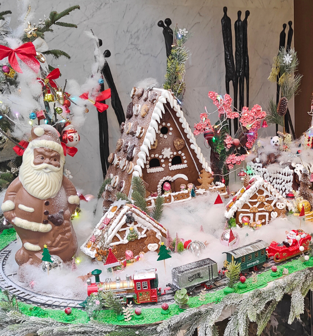 A train navigates a gingerbread village on a table, surrounded by charming candy houses and holiday decorations.