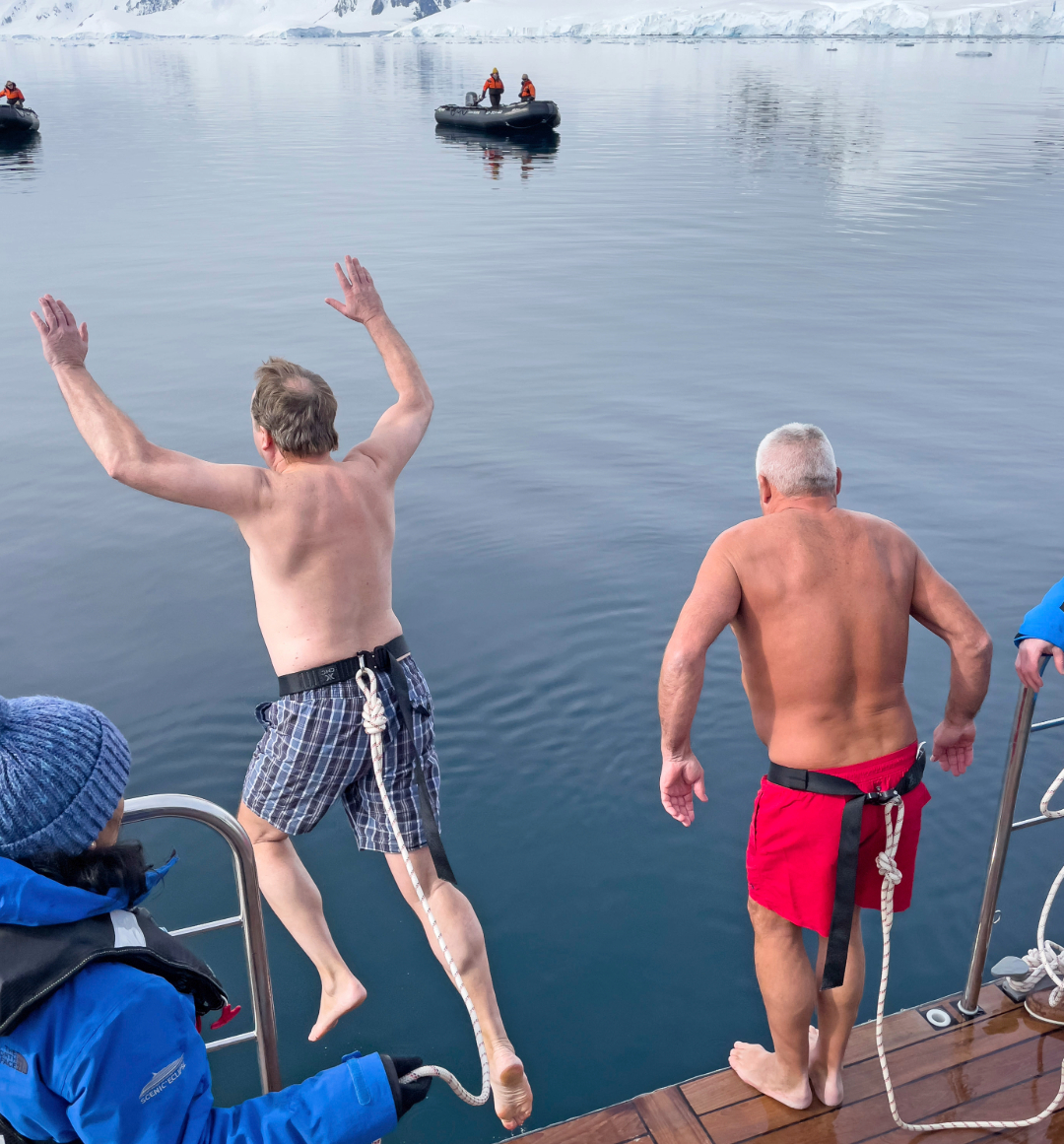 Two men mid-jump into the polar ocean