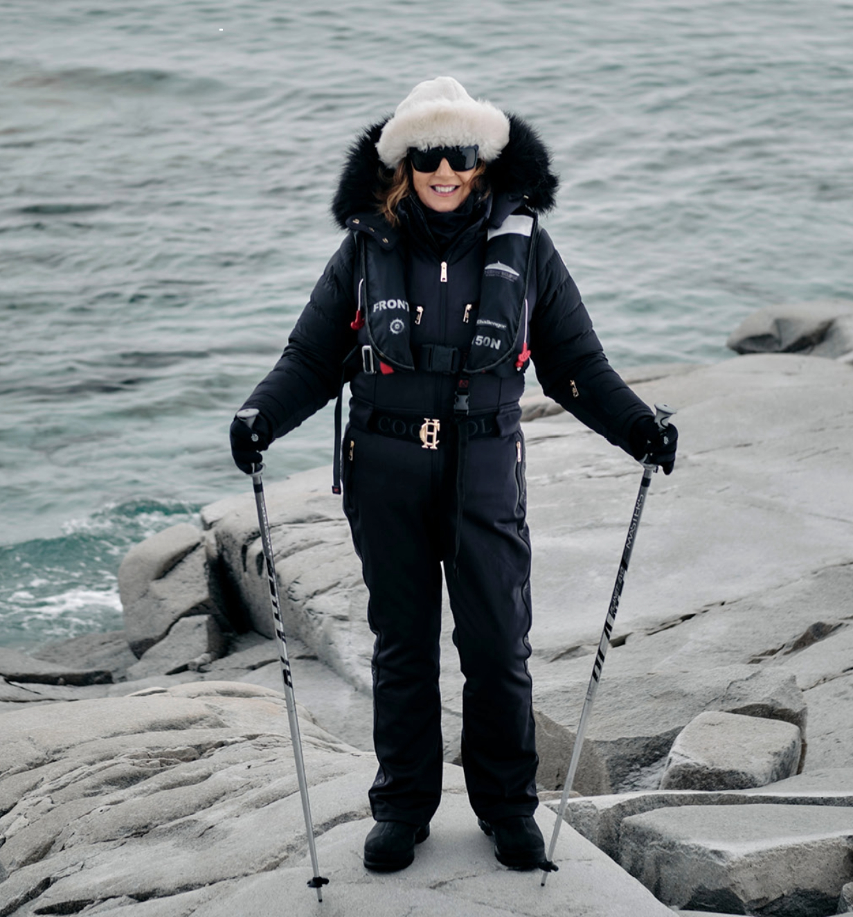 Jane McDonald in the Arctic, stood on top of a rock eqipped with hiking poles. 