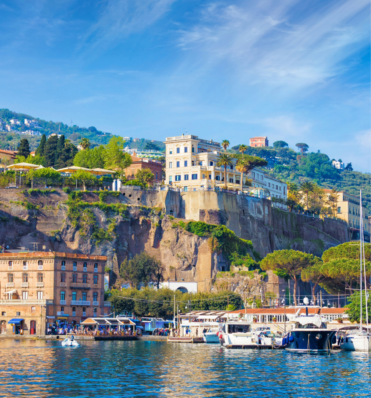 The still waters of the Sorrento coastline accompanied by docked boats and cliffs over looking the water. 