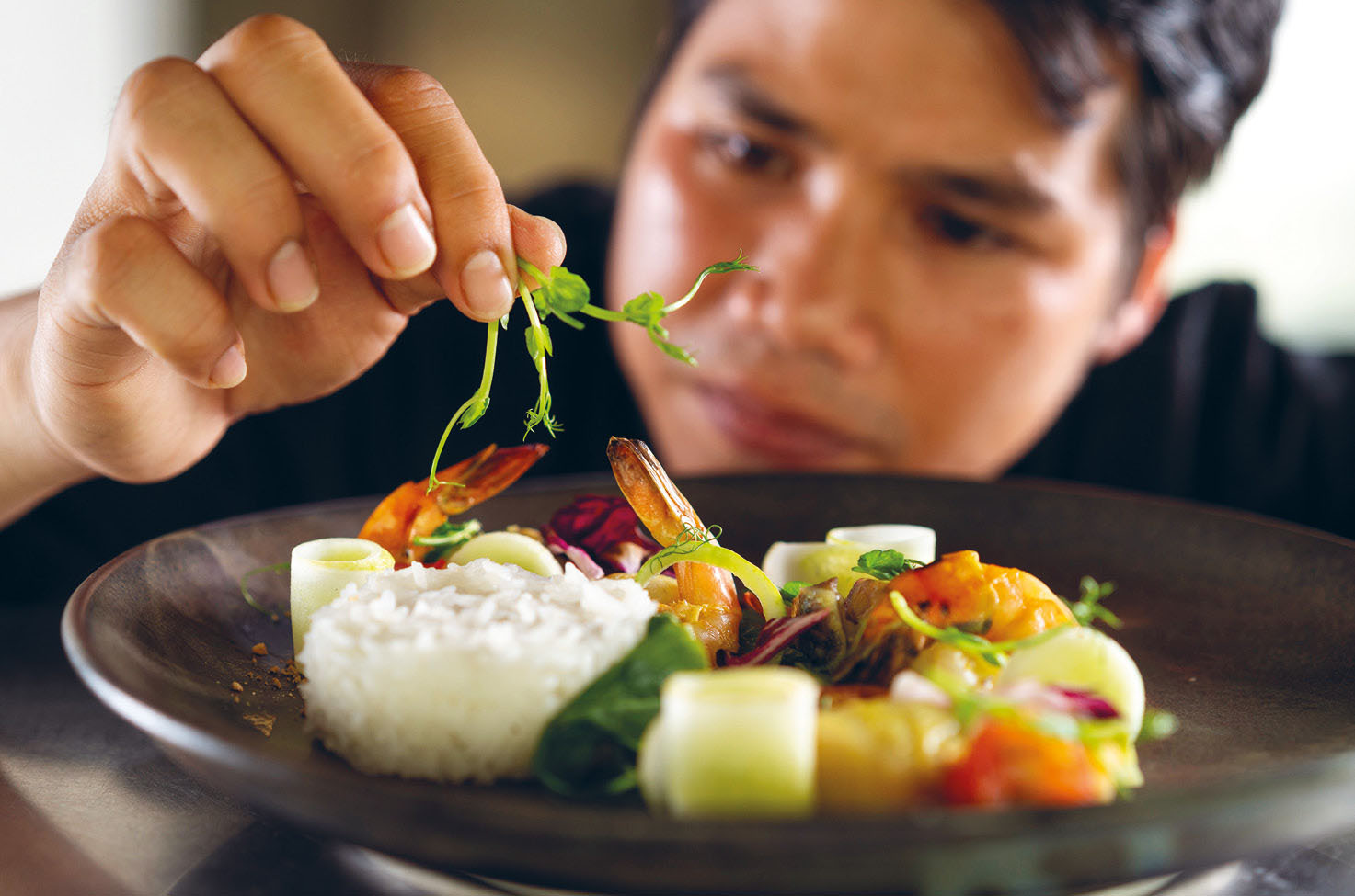 A chef placing decoration on a dish