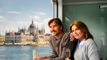 A man confidently walks along a wooden board, showcasing a selection of Gouda cheese