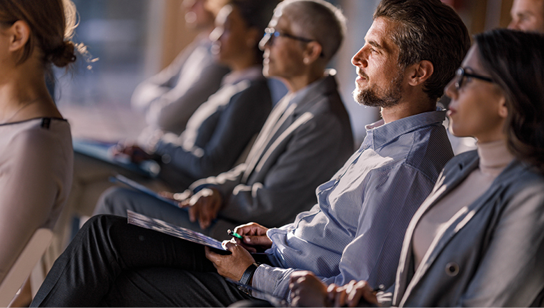 group of people sitting down wearing business attire watching a lecture