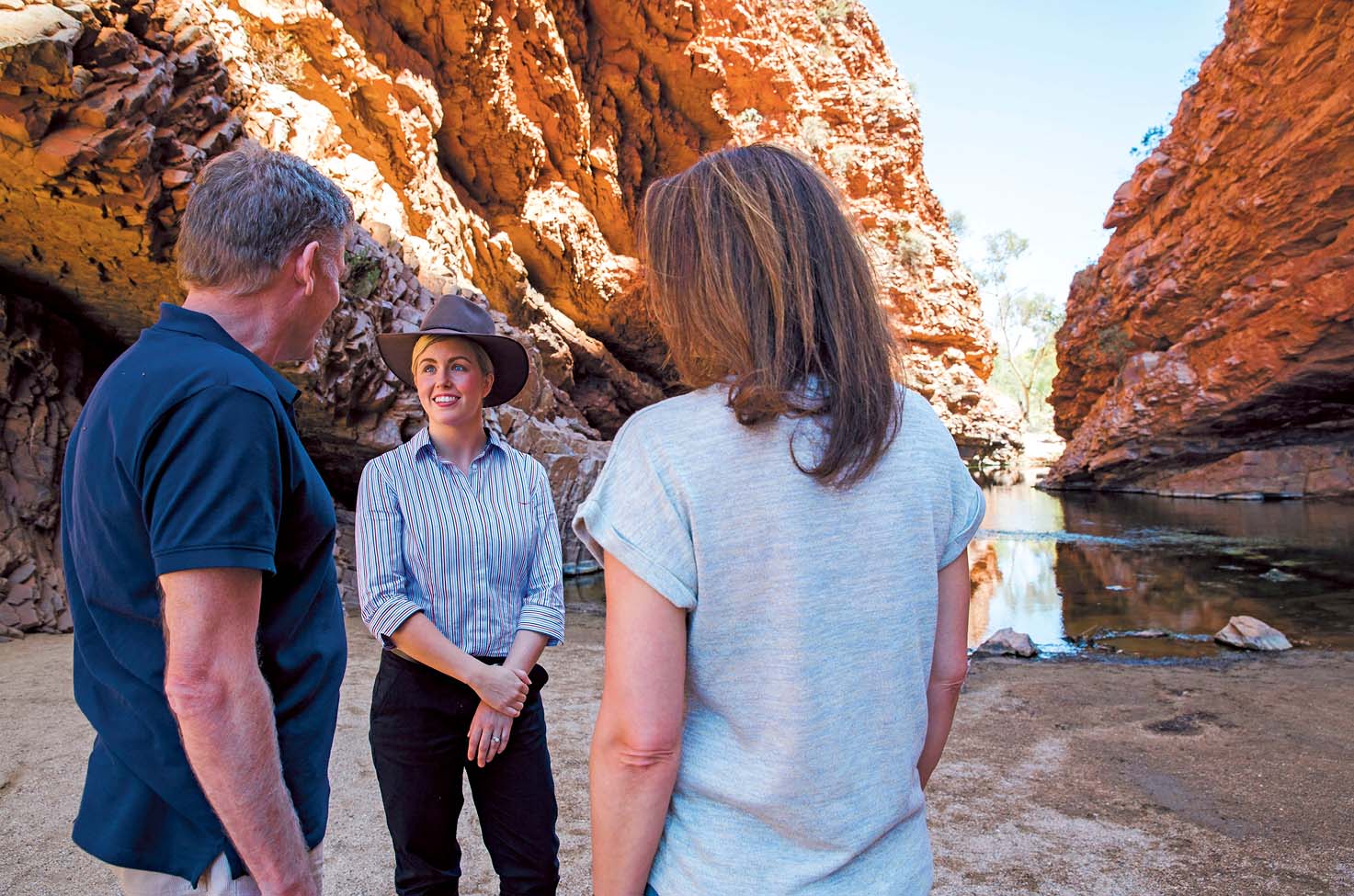 A couple stand with their guide in front of two large rock formations in Australia