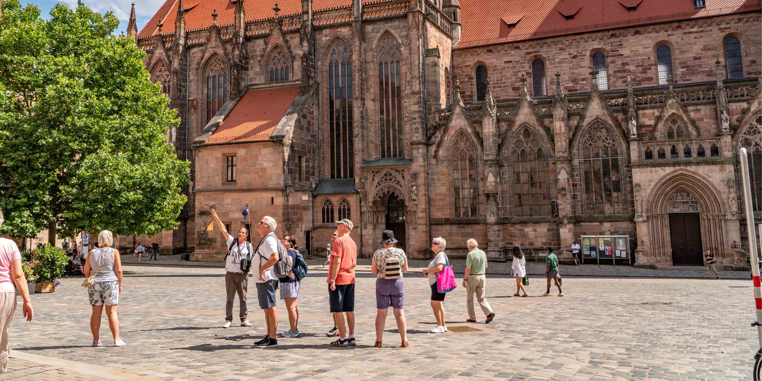 Group of tourists walking around a town square in Nuremburg following a tour guide