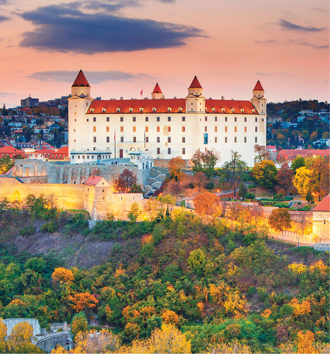Bratislava Castle surrounded by the castle walls and Autumnal greenery at sunset