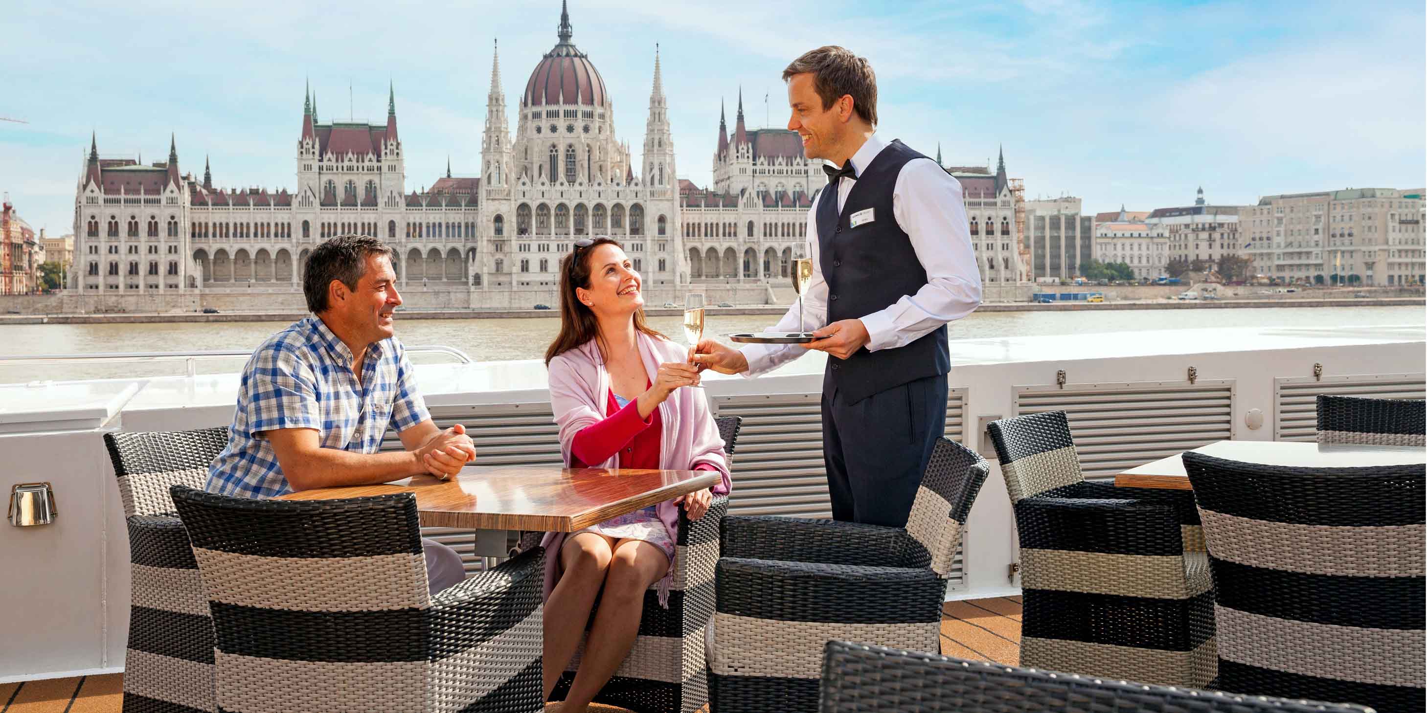 Butler serving a couple in front of the Budapest Parliament Building