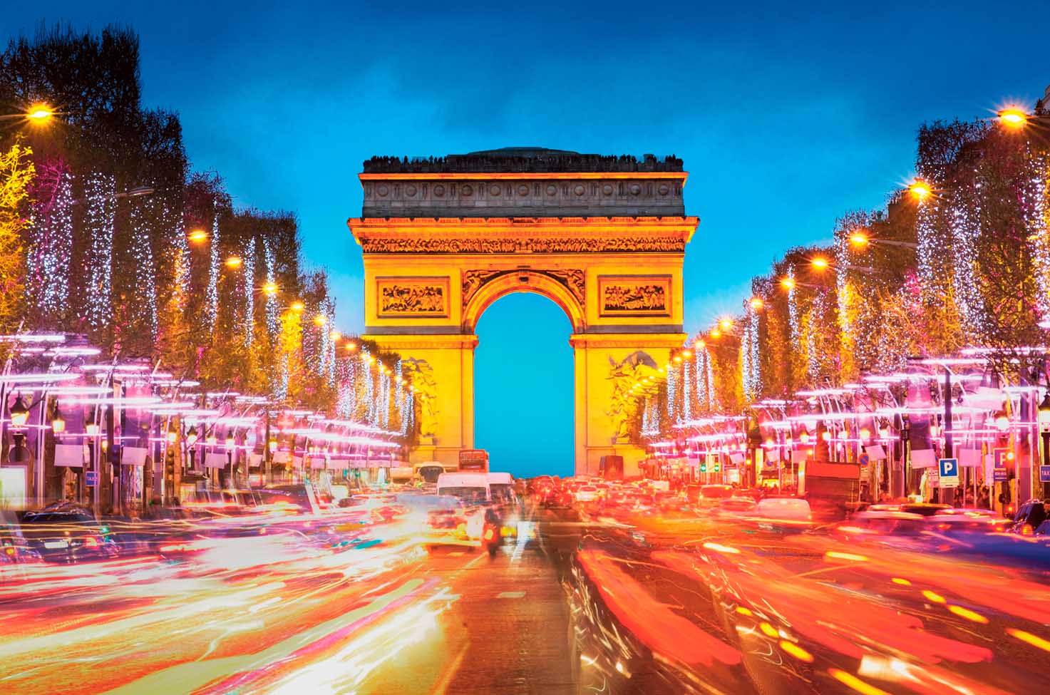 the Arc de Triomphe, Paris, illuminated at night with cars speeding past 