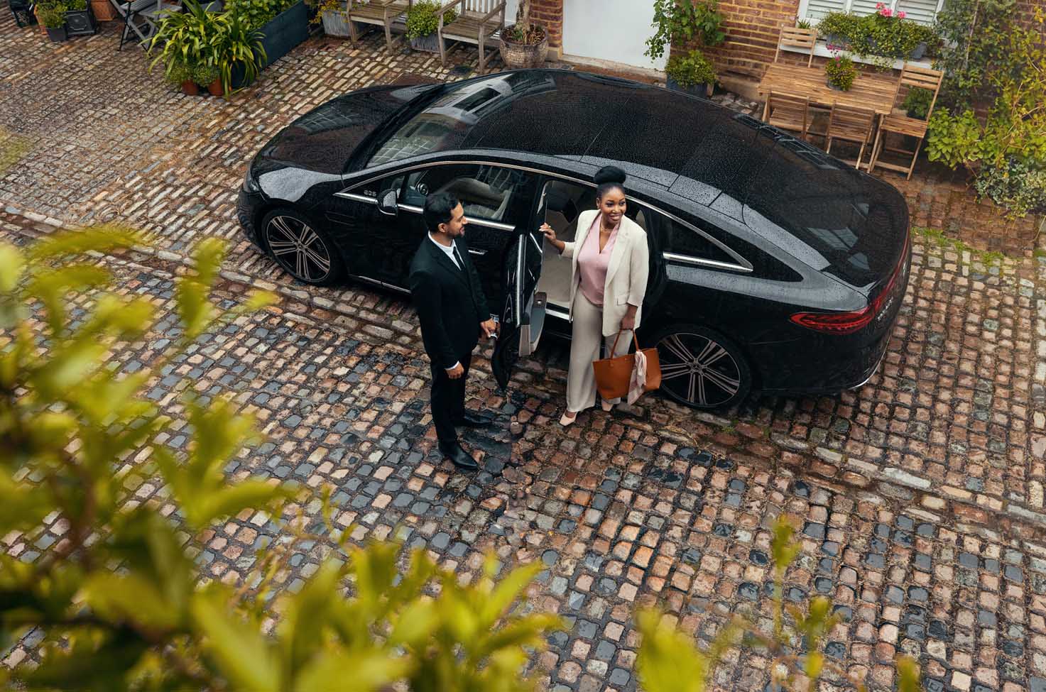 Blacklane Private Chauffeur Service driver opening door for a passenger to get out of a black luxury sedan vehicle
