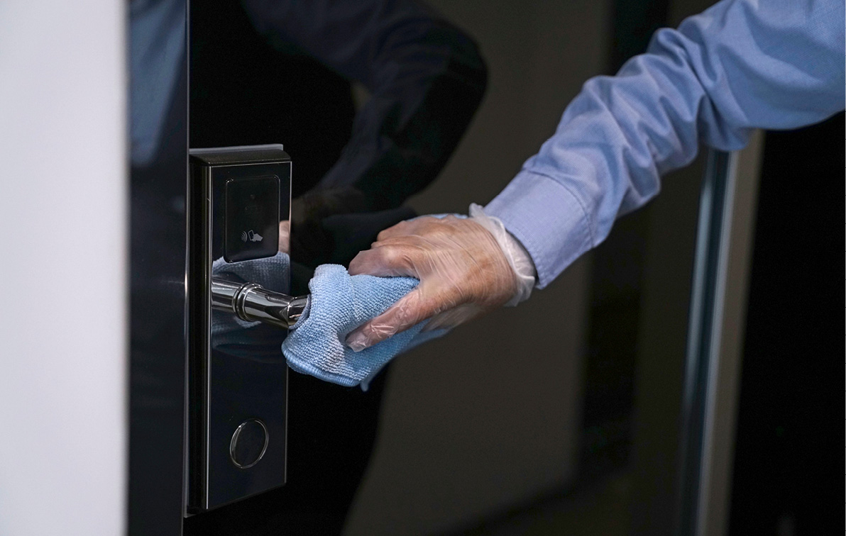 Crew wiping clean a door handle with a blue cloth