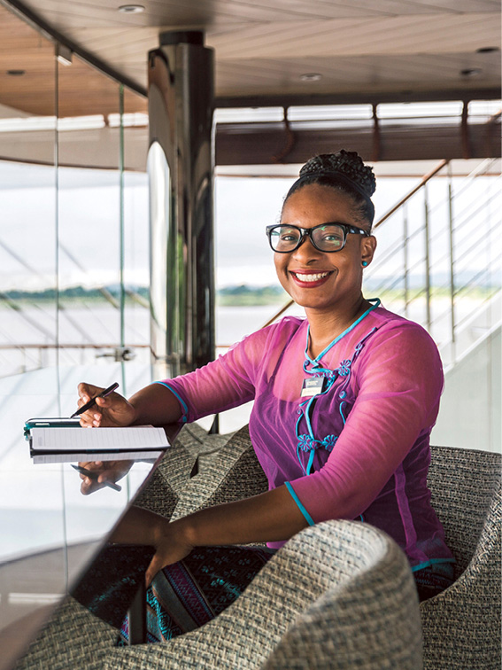 Women sitting at a desk with floor to ceiling views whilst sailing the Mekong