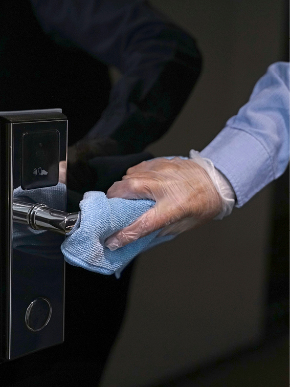 Crew wiping clean a door handle with a blue cloth
