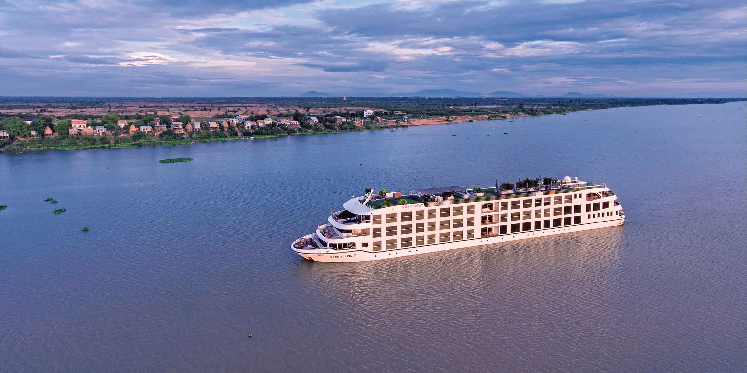 aerial shot of a river cruise ship sailing down the mekong river at sunset