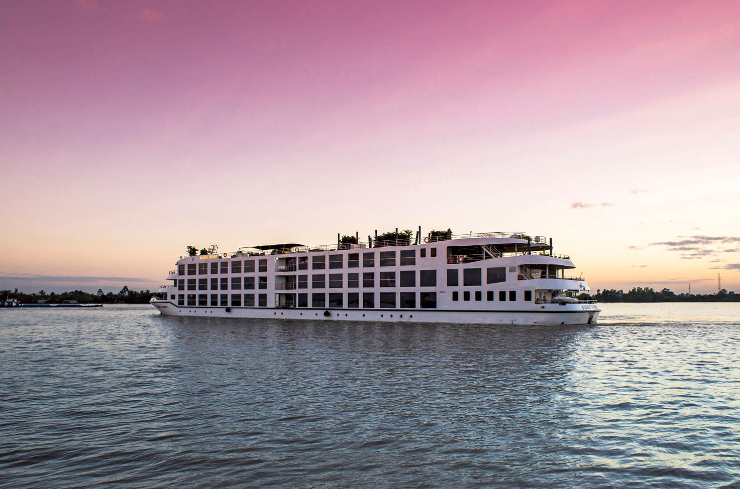 river cruise ship under a pink sunset