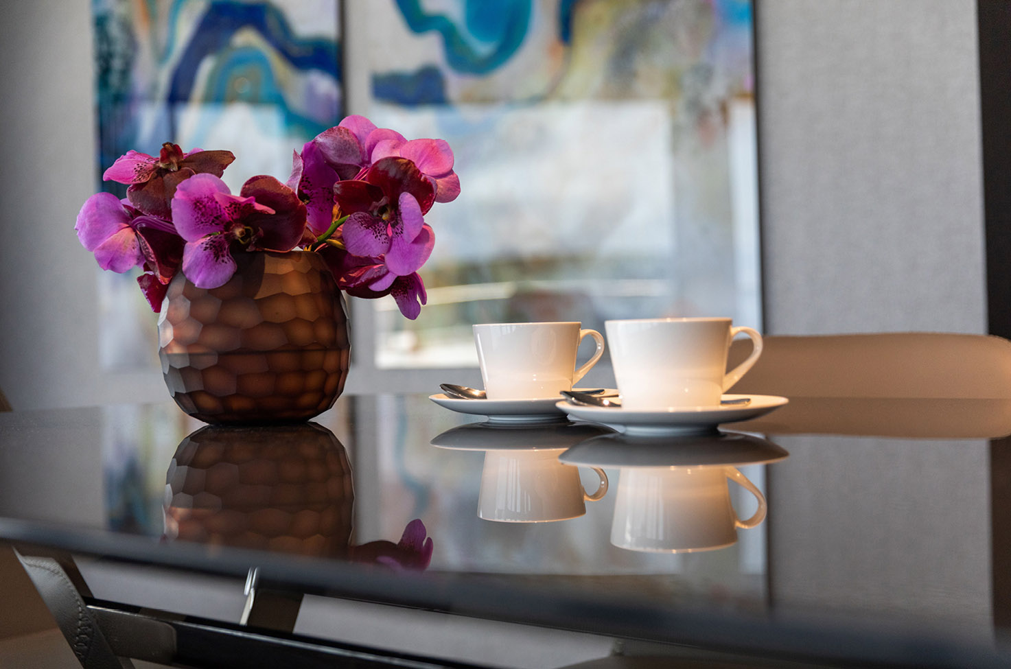 table with flowers, coffee cups and artwork in the background