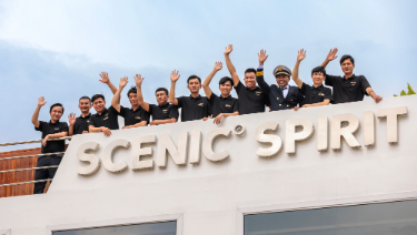 The crew of the Scenic Spirit cruise ship poses together, showcasing their uniforms and camaraderie on the deck.